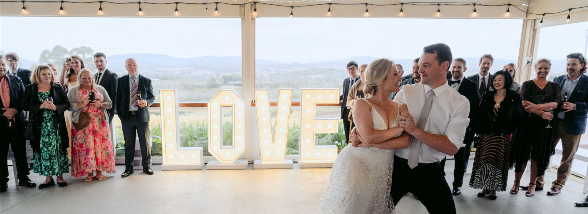 Bride and groom sharing their first dance at a wedding reception at Elmswood Estate with guests and valley views
